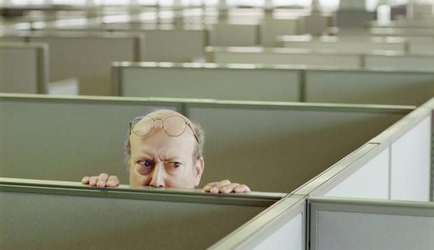 Older man hiding behind office cubicle