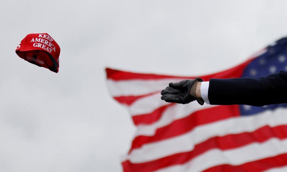 Donald Trump tosses out ‘Keep America Great’ caps at a campaign rally at Oakland County international airport in Waterford Township, Michigan, on 30 October 2020.