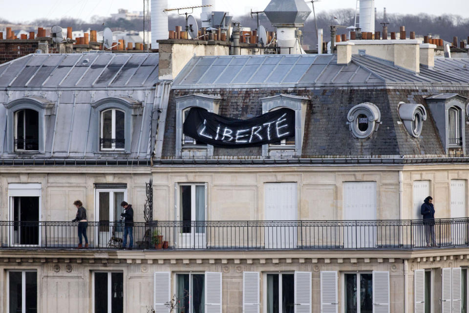 FILE - In this Jan. 11, 2015 file photo, a banner attached to a house reads "Freedom" as thousands of people gather at Republique Square in Paris. The January 2015 attacks against Charlie Hebdo and, two days later, a kosher supermarket, touched off a wave of killings claimed by the Islamic State group across Europe. Seventeen people died along with the three attackers. Thirteen men and a woman accused of providing the attackers with weapons and logistics go on trial on terrorism charges Wednesday Sept. 2, 2020. (AP Photo/Peter Dejong, File)