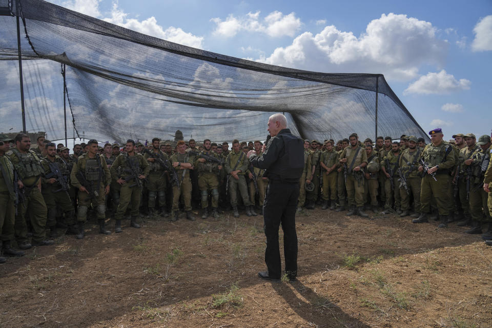 Israel's Defense Minister Yoav Gallant, wearing a protective vest, speaks with Israeli soldiers in a staging area near the border with the Gaza Strip in southern Israel, Thursday, Oct. 19, 2023. (AP Photo/Tsafrir Abayov)