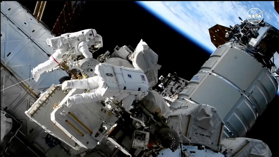 Jasmin Moghbeli, wearing a spacesuit with red stripes, works with Loral O'Hara to secure insulation around a failed radio communications unit during the fourth all-female spacewalk. / Credit: NASA TV