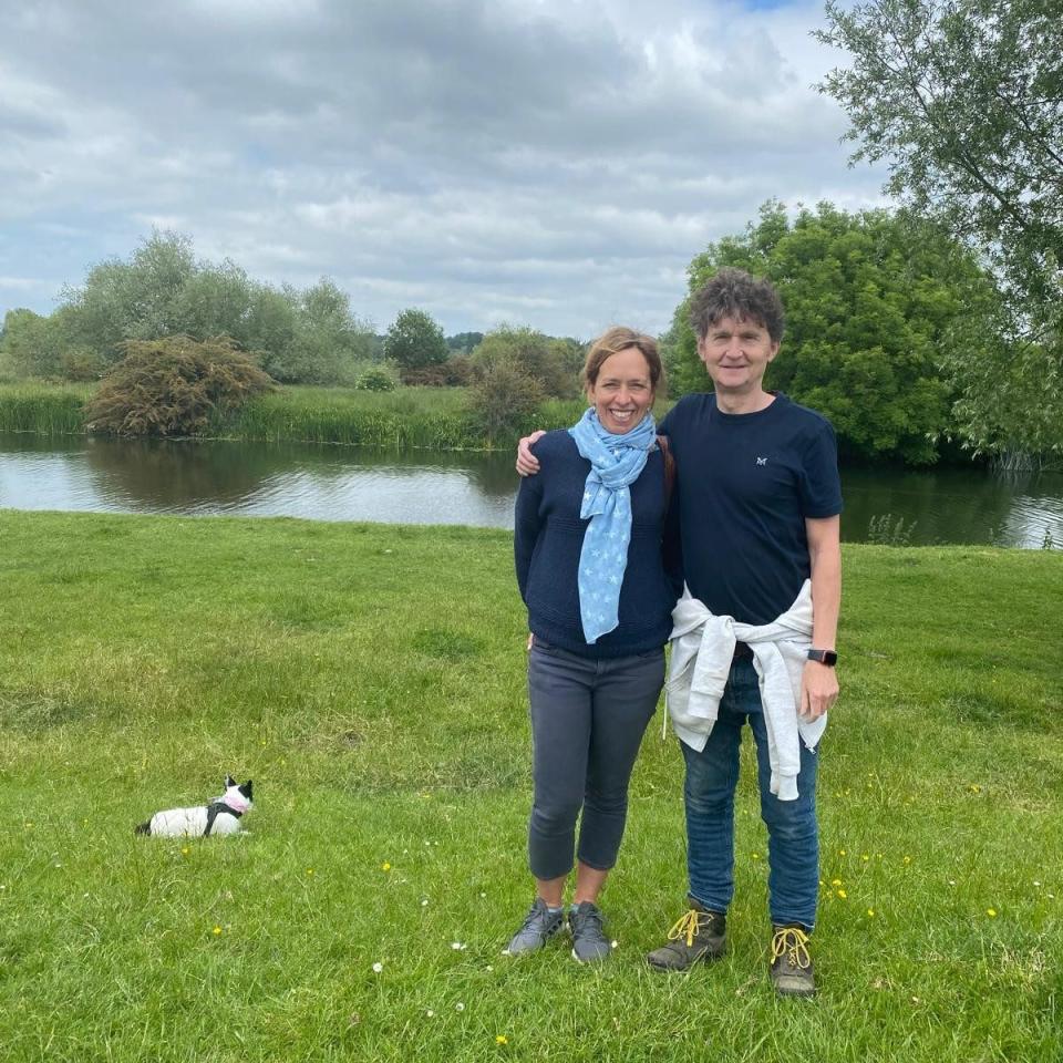 Tim Jackson and his wife smiling together while walking their dog along the River Cam