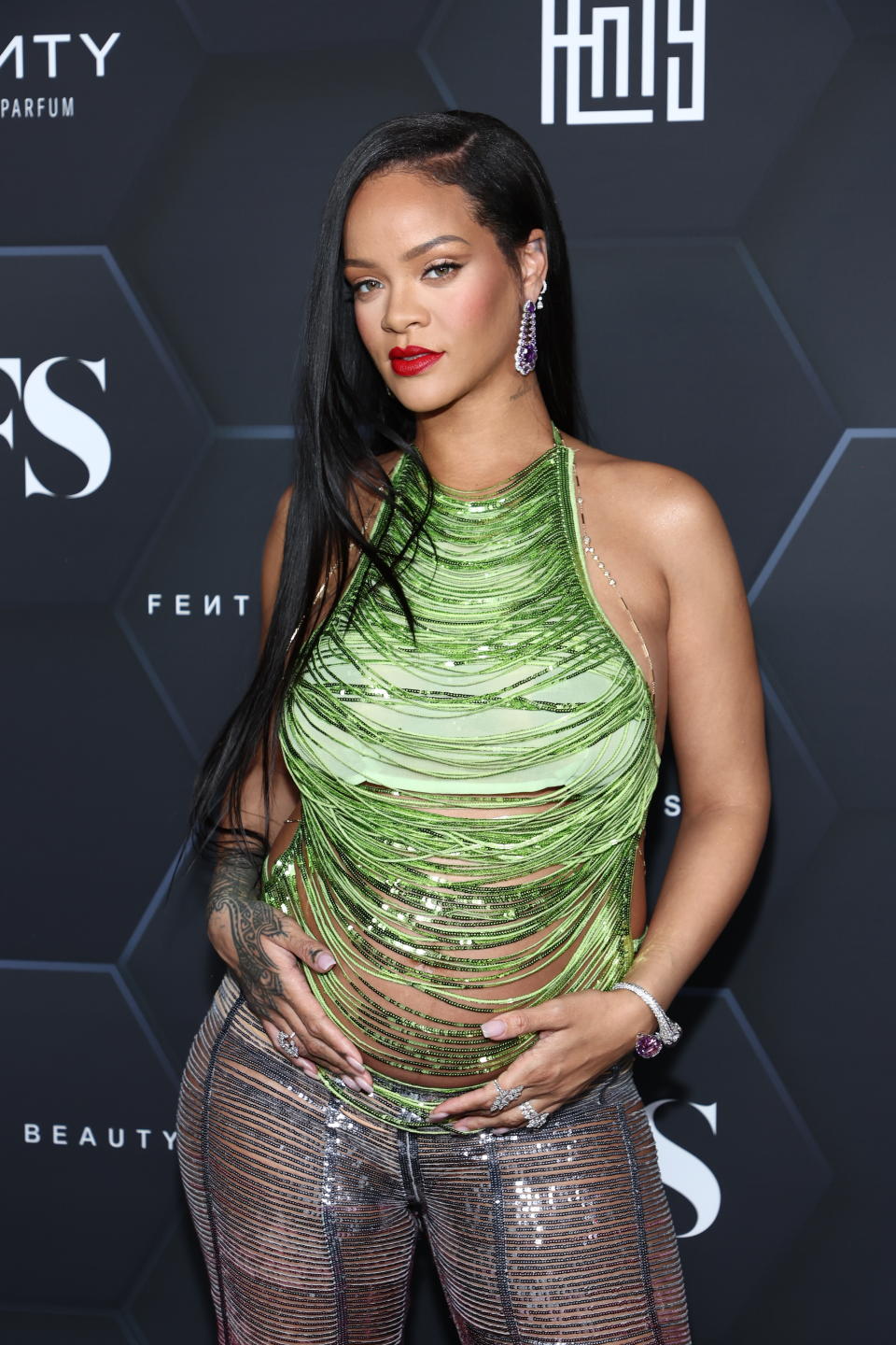 Rihanna wears Y2K look with shimmering green top and low rise trousers on red carpet. (Getty Images)