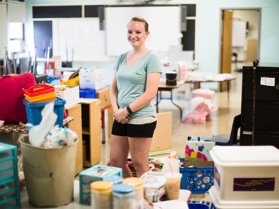 A teacher in her classroom with piles of supplies in 2016