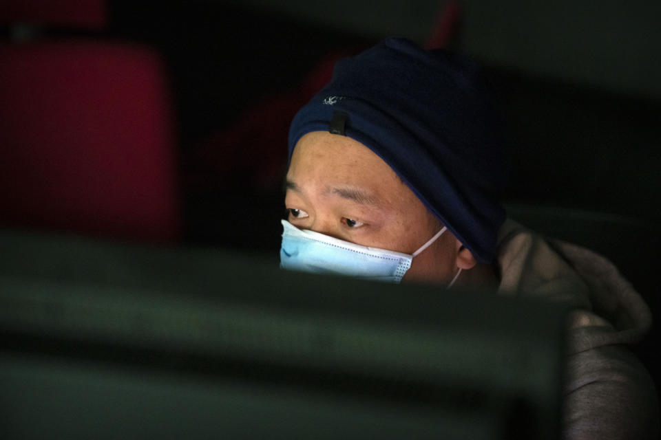 Lan Bo, director of the documentary film "Wuhan, I Am Here" watches as his movie plays in a screening room in Beijing, Saturday, Jan. 15, 2022. The homeless, the sick, the elderly: For people who fell through the cracks of the official system, the then-unprecedented decision to isolate the central Chinese city of Wuhan and its 13 million people was a matter of life or death. Director Lan Bo hopes to sound the alarm with a documentary about volunteers who helped neighbors get food and medical care following the lockdown in early 2020 of the city where the coronavirus pandemic began. (AP Photo/Mark Schiefelbein)