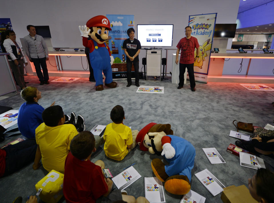 Shigeru Miyamoto (C), Nintendo's senior managing director and general manager of its Entertainment Analysis and Development division, and Takashi Tezuka (R), executive officer of Nintendo's Entertainment Analysis and Development division, together with Nintendo's character Mario (L), introduce a new game "Mario Maker" while a small group of children look on during a news conference at the 2014 Electronic Entertainment Expo, known as E3, in Los Angeles, California June 11, 2014.  REUTERS/Kevork Djansezian  (UNITED STATES - Tags: SCIENCE TECHNOLOGY SOCIETY BUSINESS TPX IMAGES OF THE DAY)