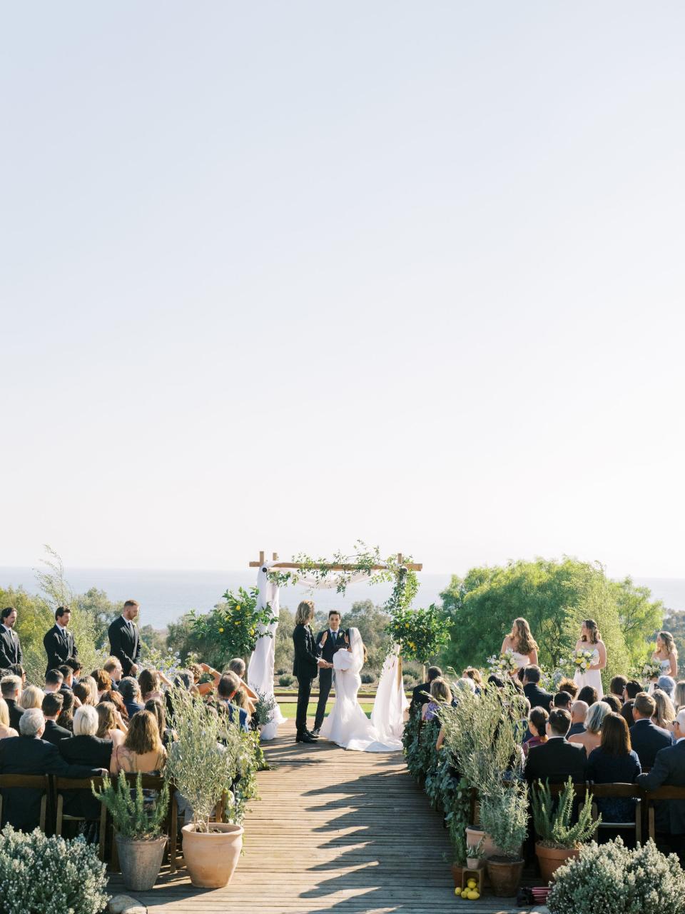 A bride and groom look at each other at the wedding altar in front of a large group.