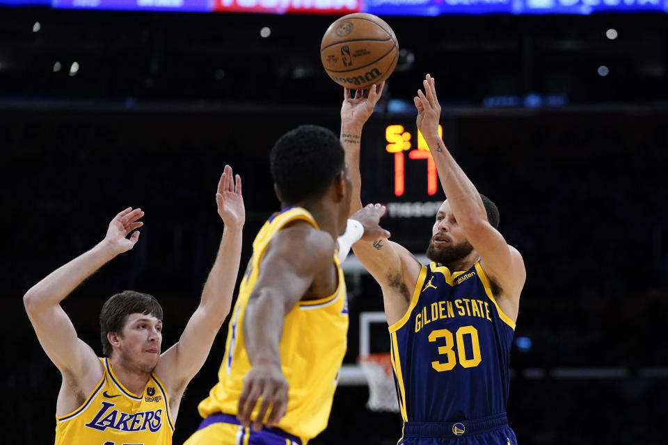 Golden State Warriors guard Stephen Curry, right, shoots against Los Angeles Lakers guard Austin Reaves, left, and forward Rui Hachimura during the first half of an NBA basketball game Tuesday, April 9, 2024, in Los Angeles. (AP Photo/Ryan Sun)