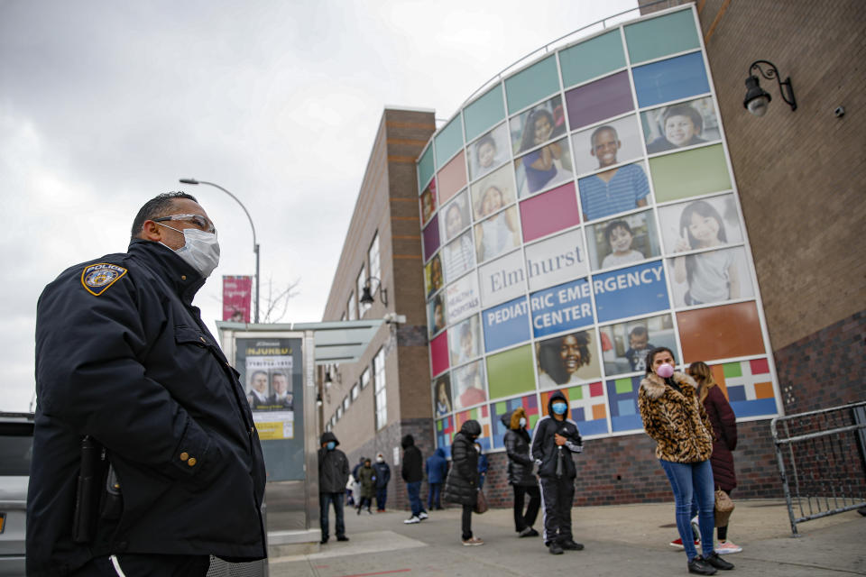 FILE - In this Wednesday, March 25, 2020 file photo, an NYPD officer wears personal protective equipment while maintaining order along a line to enter COVID-19 testing site at Elmhurst Hospital Center in New York. Police have stepped up efforts to pressure New Yorkers to practice social distancing at the epicenter of the crisis. (AP Photo/John Minchillo, File)