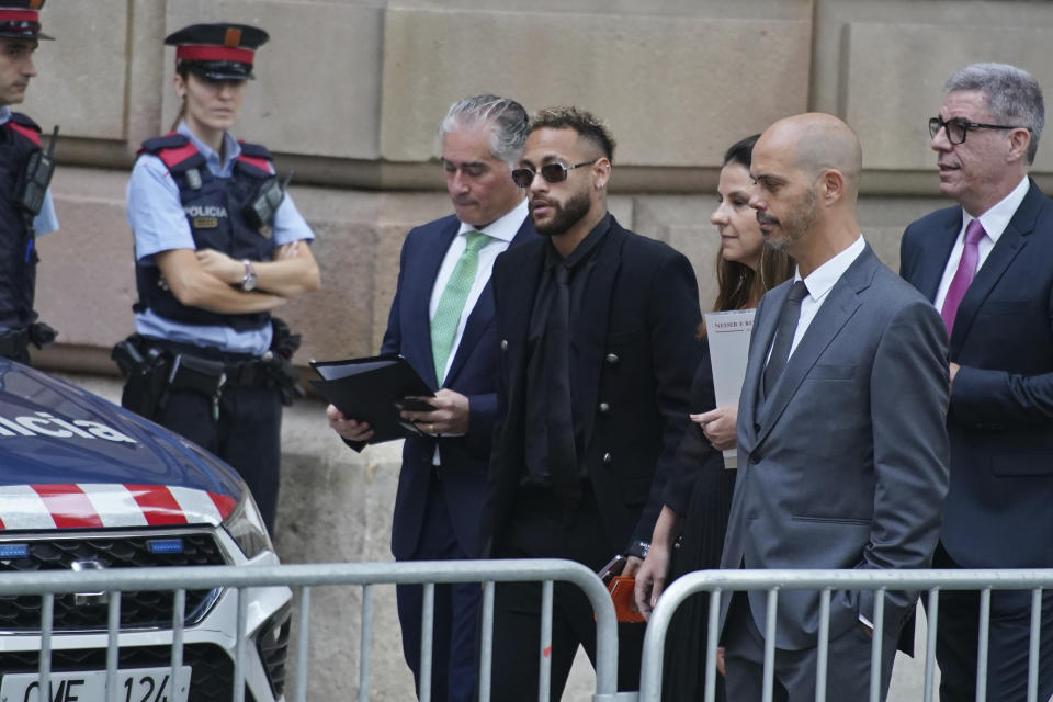 Former FC Barcelona player Neymar who now plays for Paris Saint-Germain, centre, arrives at a court in Barcelona, Spain, Monday Oct. 17, 2022. Neymar returned to Spain Monday to face trial on fraud charges regarding his 2013 transfer from Santos to FC Barcelona. The Brazilian forward, his father, and the former executives of Barcelona and Santos are accused of hiding the true cost of his transfer with the alleged goal of cheating a private Brazilian company.(AP Photo/Joan Mateu Parra)