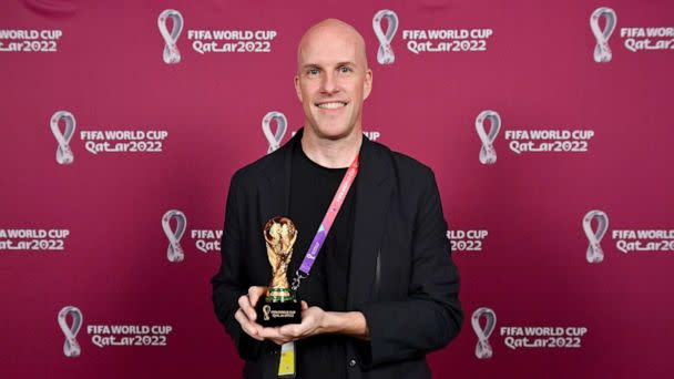 PHOTO: Grant Wahl smiles as he holds a World Cup replica trophy during an award ceremony in Doha, Qatar on Nov. 29, 2022. (Brendan Moran/AP, FILE)