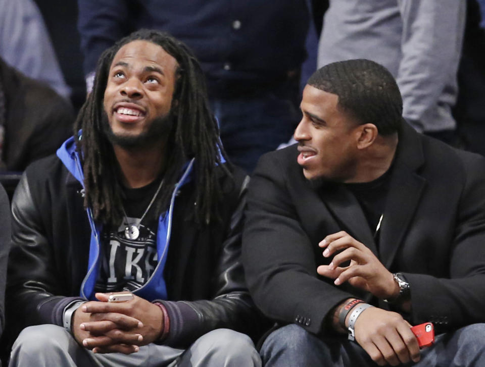 Seattle Seahawks cornerback Richard Sherman, left, and linebacker Bobby Wagner watch the Toronto Raptors in the first half of an NBA basketball game against the Brooklyn Nets at the Barclays Center, Monday, Jan. 27, 2014, in New York. (AP Photo/Kathy Willens)