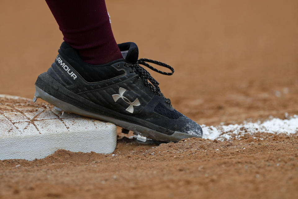 FILE - In this May 3, 2019, file photo a Texas Southern University's softball player's Under Armour cleats touch the third base bag during a NCAA softball game in Houston. Under Armour last week said it would up to $425 million in restructuring charges as it tries to reverse a decline in sales in ’s latest warning about sales and costs put another dent in its stock price and added to a years-long decline. (AP Photo/Aaron M. Sprecher, File)