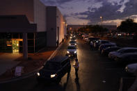 FILE - In this Nov. 2, 2020, file photo, people wait in line in their cars to drop off mail-in ballots in a drive-thru mail-in ballot drop off area at the Clark County Election Department in Las Vegas. The county officials who run elections are facing a slate of new punishments as part of a nationwide Republican campaign to roll back access to the ballot, months after many hailed them as heroes for the creative ways they expanded voting access last year during the coronavirus outbreak. (AP Photo/John Locher, File)