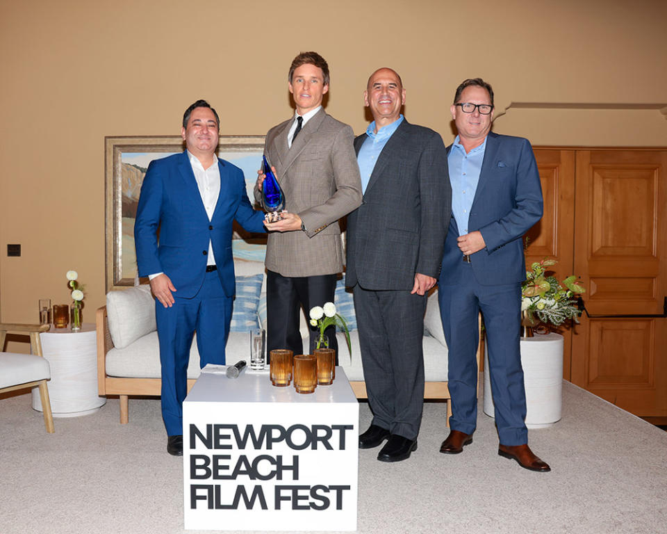 (L-R) THR Executive Editor Scott Feinberg, NBFF Icon Award Honoree Eddie Redmayne, Newport Beach Film Festival Co-founder & CEO Gregg Schwenk, and Newport Beach Film Festival Co-founder & Director of Marketing Todd Quartararo pose onstage at THR’s "Awards Chatter" with Eddie Redmayne during the 2022 Newport Beach Film Festival at The Resort at Pelican Hill on October 15, 2022 in Newport Beach, California.