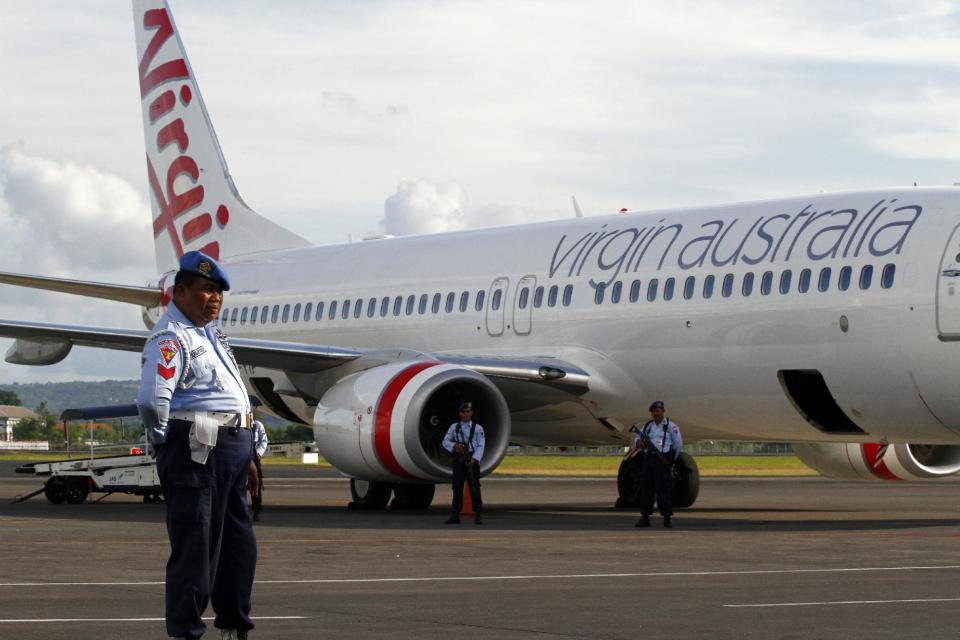 Indonesian Air Force personnel stand guard by a Virgin Australia airplane in Bali, Indonesia, Friday, April 25, 2015. A drunken passenger who caused a hijack scare on a Virgin Australia flight by trying to break into the cockpit was arrested Friday after the plane landed on Indonesia's resort island of Bali, officials said. (AP Photo/Firdia Lisnawati)