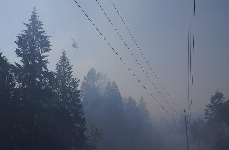 A water-drop helicopter flies Wednesday, Sept. 9, 2020, near a wildfire burning in Bonney Lake, Wash., south of Seattle. (AP Photo/Ted S. Warren, Pool)