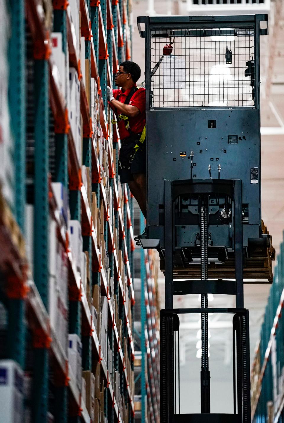 An employee reaches for supplies on a shelf at the Uline warehouse in Naples on Tuesday, April 18, 2023.