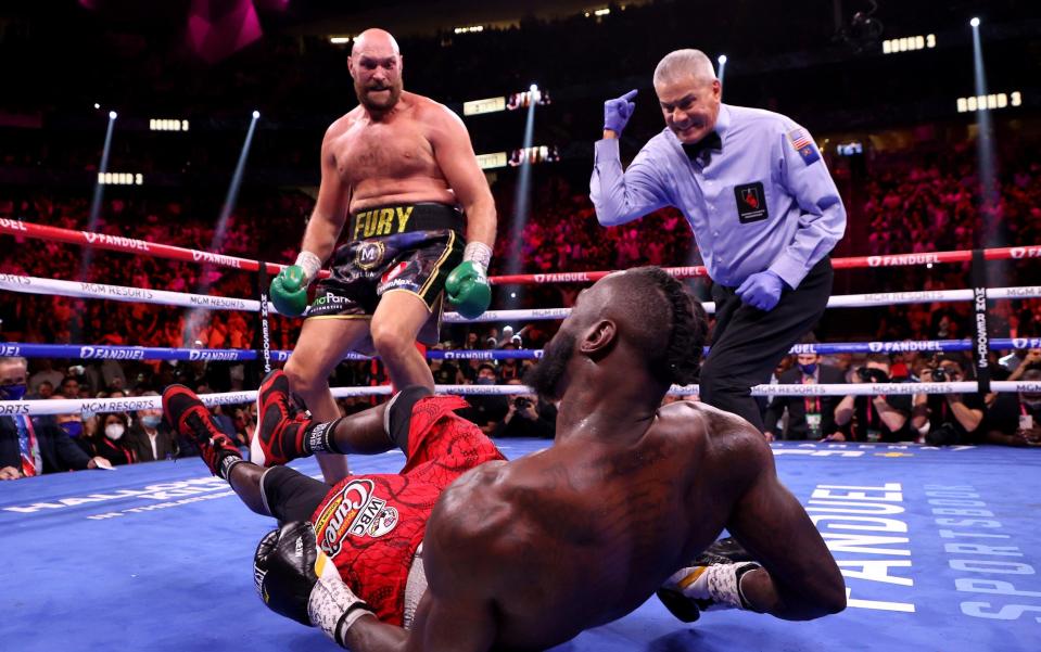 Tyson Fury (top) reacts after knocking down Deontay Wilder in the third round of their WBC Heavyweight Championship title fight at T-Mobile Arena on October 09, 2021 in Las Vegas, Nevada - GETTY IMAGES