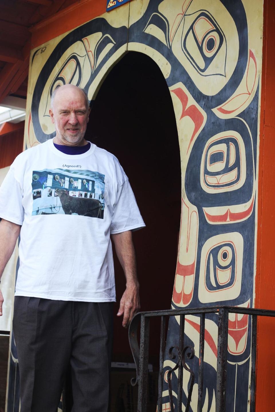 This April 2013 photo shows resident Richard Ormbrek standing beneath the doorway of his house, which was once known as "The Totem House" among local residents, for the enormous Tlingit Haida painting on the side of the home in Seattle. The totem archway is the last remaining vestige of the totem artwork. (AP Photo/Cedar Burnett)