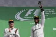 Formula One - F1 - Mexican F1 Grand Prix - Mexico City, Mexico - 30/10/16 - Second placed finisher Mercedes driver Nico Rosberg of Germany (L) applauds as his teammate, race winner Lewis Hamilton of Britain, celebrates with his trophy. REUTERS/Henry Romero