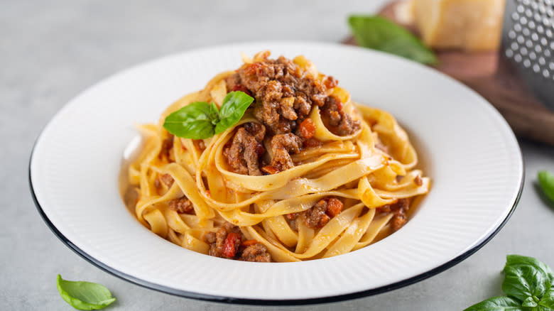 Tagliatelle with ragu on white plate with black rim