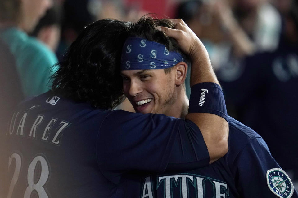 Seattle Mariners' Sam Haggerty, right, is hugged by Eugenio Suarez after Haggerty scored on a single by Ty France during the sixth inning of the team's baseball game against the Los Angeles Angels on Tuesday, Aug. 16, 2022, in Anaheim, Calif. (AP Photo/Marcio Jose Sanchez)