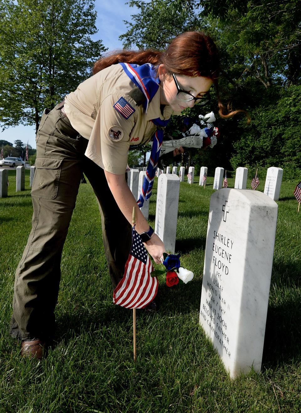 Mya Powell, 16, from Troop 1310 of Auburn, places flowers on relatives' graves after finishing putting flags in front of graves at Camp Butler National Cemetery on Saturday as part of the traditional placing of flags by Scouts prior to Memorial Day. [Thomas J. Turney/The State Journal-Register]