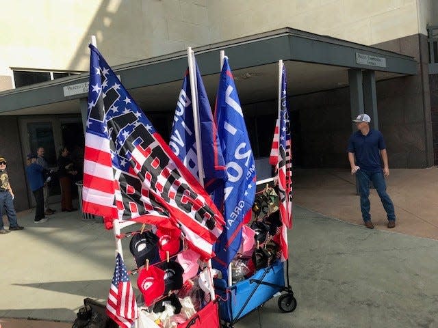 A cart full of merchandise sits outside the Austin Convention Center on Saturday before the arrival of former President Donald Trump. Items for sale included T-shirts, flags with messages of support for Trump and the signature red hats that are at all of his road shows.