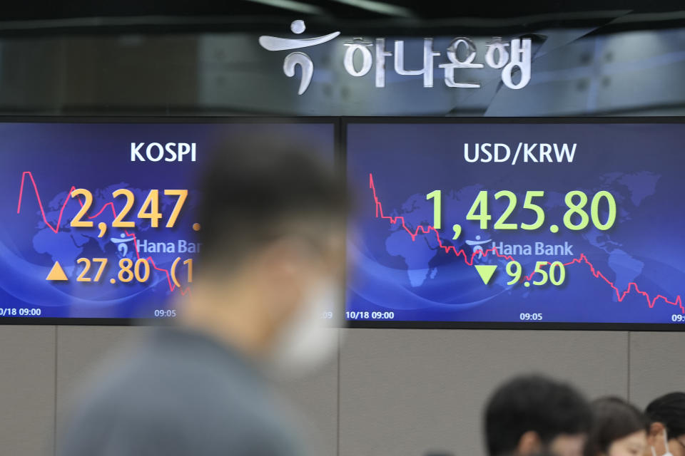 A currency trader walks by the screens showing the Korea Composite Stock Price Index (KOSPI), left, and the foreign exchange rate between U.S. dollar and South Korean won at a foreign exchange dealing room in Seoul, South Korea, Tuesday, Oct. 18, 2022. Stocks were mostly higher in Asia on Tuesday after Wall Street rallied in its latest about-face in recent topsy-turvy trading. (AP Photo/Lee Jin-man)