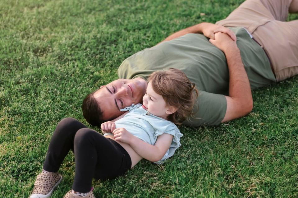 Father and daughter laying in grass via Getty Images