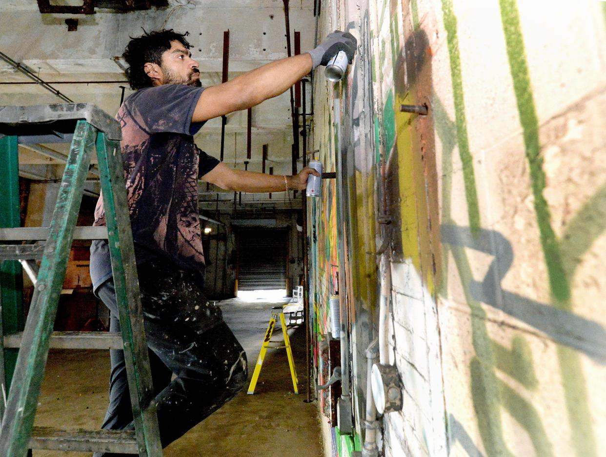 Graffiti artist Alex Smith works on one of his creations at the former Pillsbury Mills plant Wednesday, Nov. 8, 2023 as part of an art exhibit for Moving Pillsbury Forward.