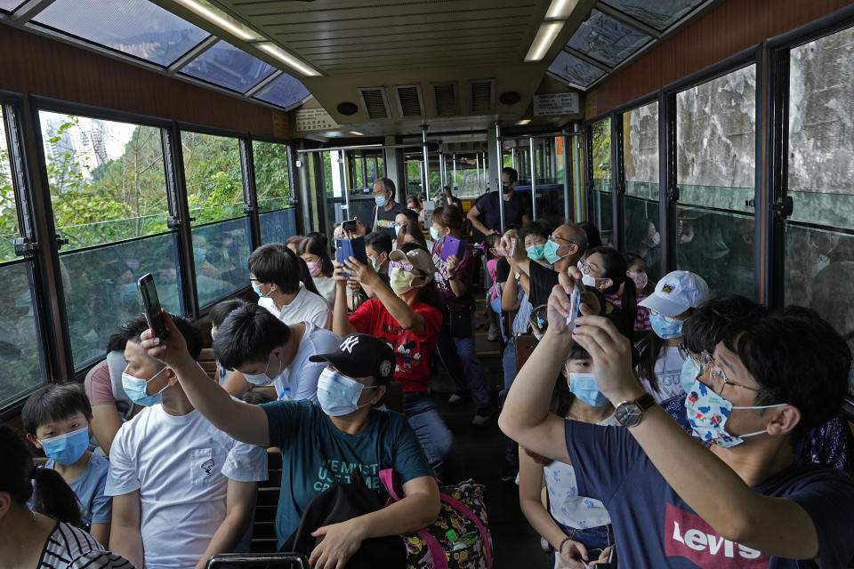 Passengers take photos from a Peak Tram during a tram journey in Hong Kong on June 17, 2021. Hong Kong’s Peak Tram is a fixture in the memories of many residents and tourists, ferrying passengers up Victoria Peak for a bird’s eye view of the city’s many skyscrapers. (AP Photo/Vincent Yu)