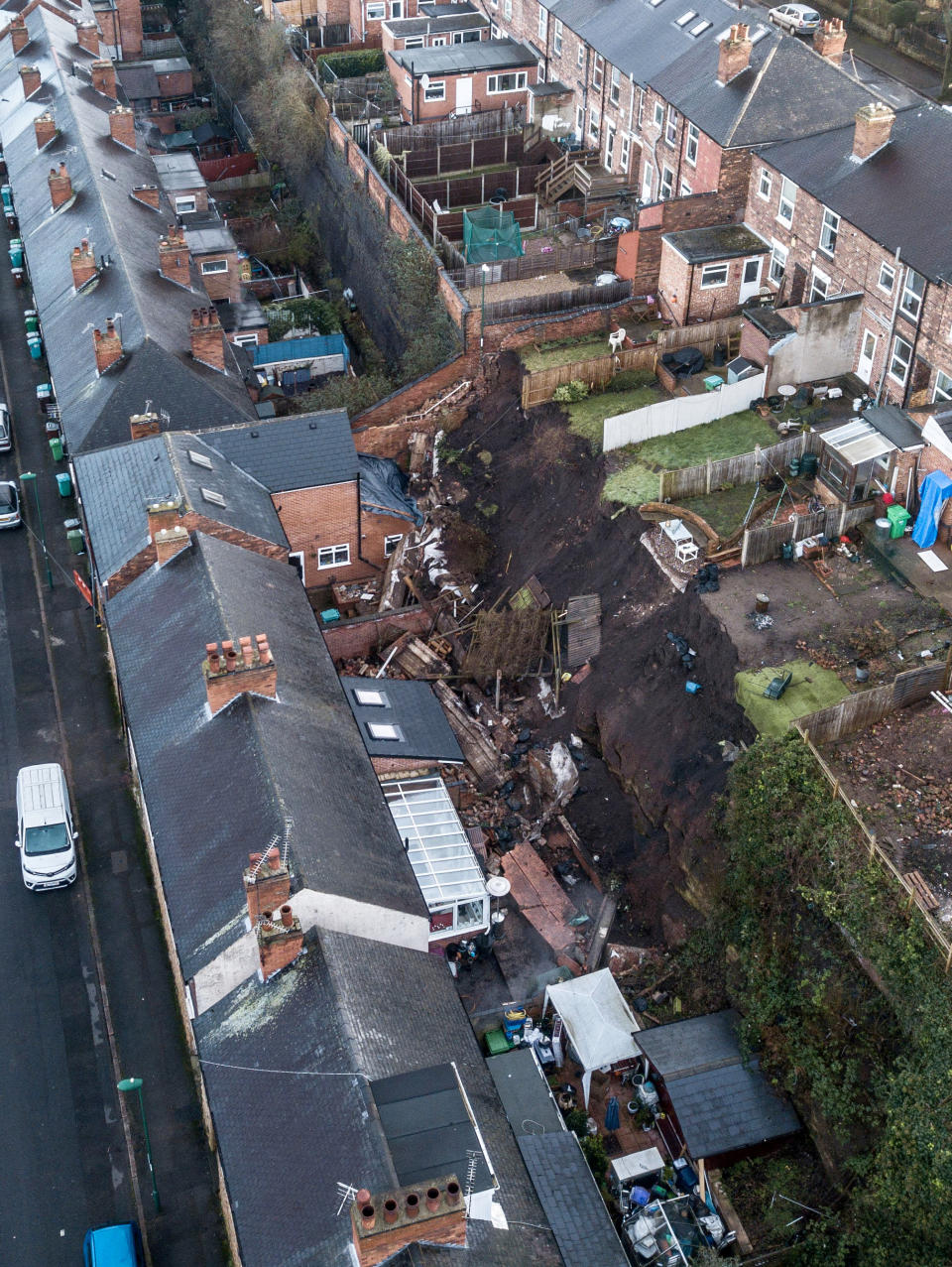 A 70 foot wall has fallen into the gardens of properties in Nottingham after heavy rainfall, February 04, 2021.  Five families were evacuated from their homes in the middle of the night after reports of a 'landslide' in Nottingham.  See SWNS story SWMDwall.  Distressed residents were woken up by the noise of a tonne of bricks, rubble and earth falling into their back gardens of their terraced houses after a 70-foot high wall collapsed.  Nottinghamshire police said five families from four houses had to be evacuated in the pouring rain in Sneinton at 1am on February 3.  Officers arrived at the scene to discover severe damage to their homes, with bathrooms and kitchens flooded.