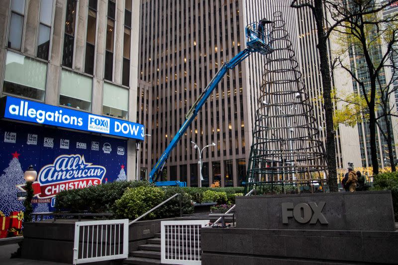 Workers clean up the burnt remains of a Christmas tree outside the News Corp. and Fox News building in New York