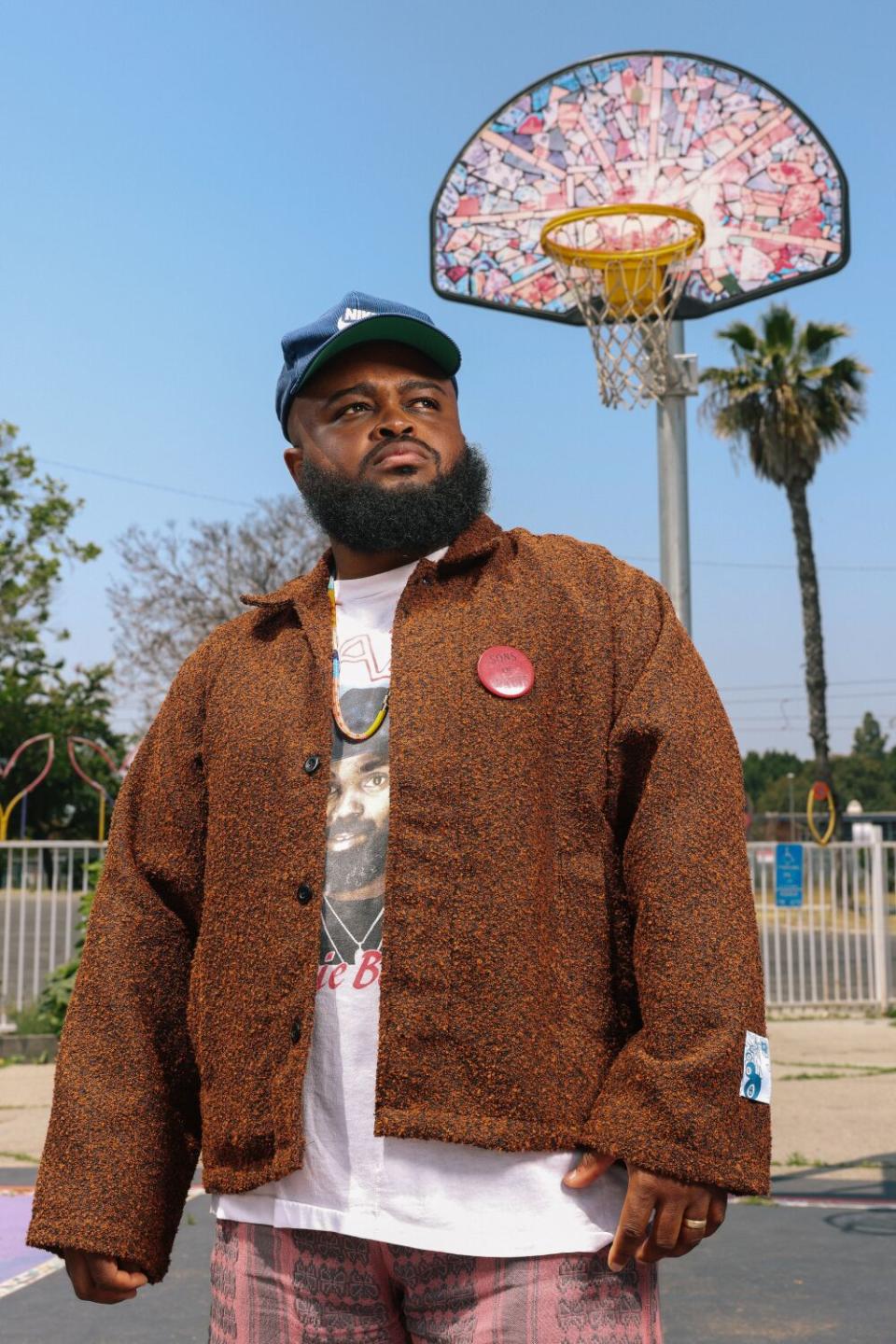 A man looks off into the distance in front of the Watts Towers.