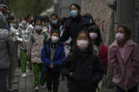 Students wearing face masks to protect from COVID-19 are escorted by a teacher as they leave school after classes in Beijing, Monday, Nov. 29, 2021. Despite the global worry, scientists caution that it's still unclear whether the omicron COVID-19 variant is more dangerous than other versions of the virus that has killed more than 5 million people. Some countries are continuing with previous plans to loosen restrictions, with signs of reopening in Malaysia, Singapore and New Zealand. (AP Photo/Andy Wong)