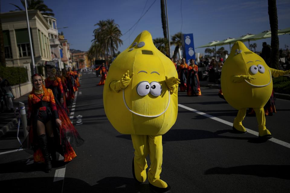 A carnival worker dressed as a lemon dances in the street during the 90th edition of the Lemon Festival in Menton, France, Saturday, Feb. 17, 2024. (AP Photo/Daniel Cole)