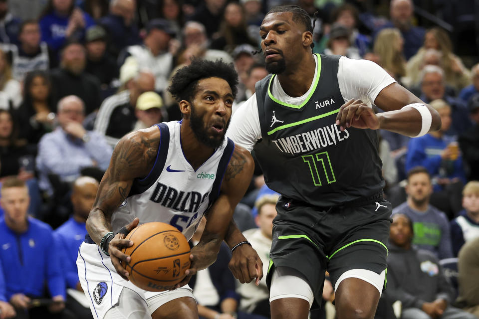 Dallas Mavericks forward Derrick Jones Jr., left, works toward the basket as Minnesota Timberwolves center Naz Reid (11) defends during the first half of an NBA basketball game, Thursday, Dec. 28, 2023, in Minneapolis. (AP Photo/Matt Krohn)