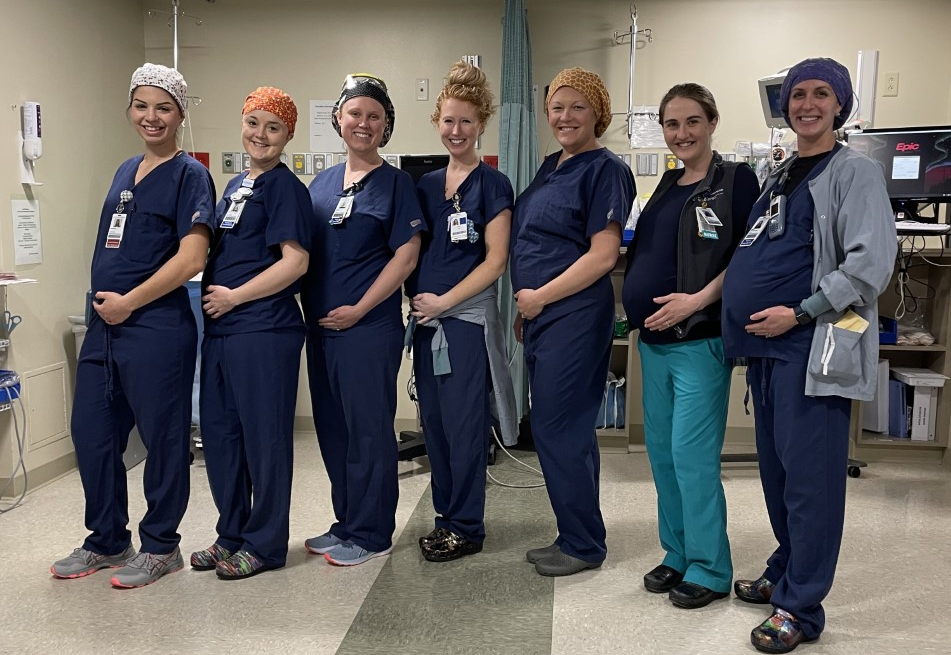 Picture here are seven of the women expecting by order of due date. Serena Swanson, CRNA-delivered May 2023; Jenny Miles, RN SDS-due June 2023; Jen Jones, CRNA-due July 2023; Emily Piche, RN PACU-due August 2023; Alexa Hayes, CRNA-due September 2023; Grace McManus, Surgical Technologist-due September 2023; Elizabeth Sullivan, Anesthesia Technologist-due October 2023