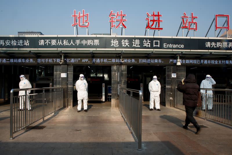 Workers take the body temperature of passengers before they enter the subway station outside the Beijing Railway Station in Beijing