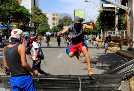 Demonstrators jump over a barricade while clashing with riot security forces during a strike called to protest against Venezuelan President Nicolas Maduro's government in Caracas, Venezuela, July 20, 2017. REUTERS/Marco Bello