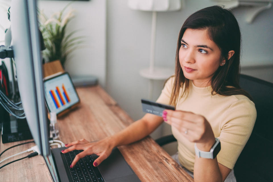 Young woman working at home is using credit card for online payments