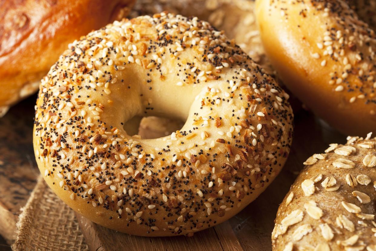 Focus on an everything bagel, surrounded by three other bagels with a rustic background