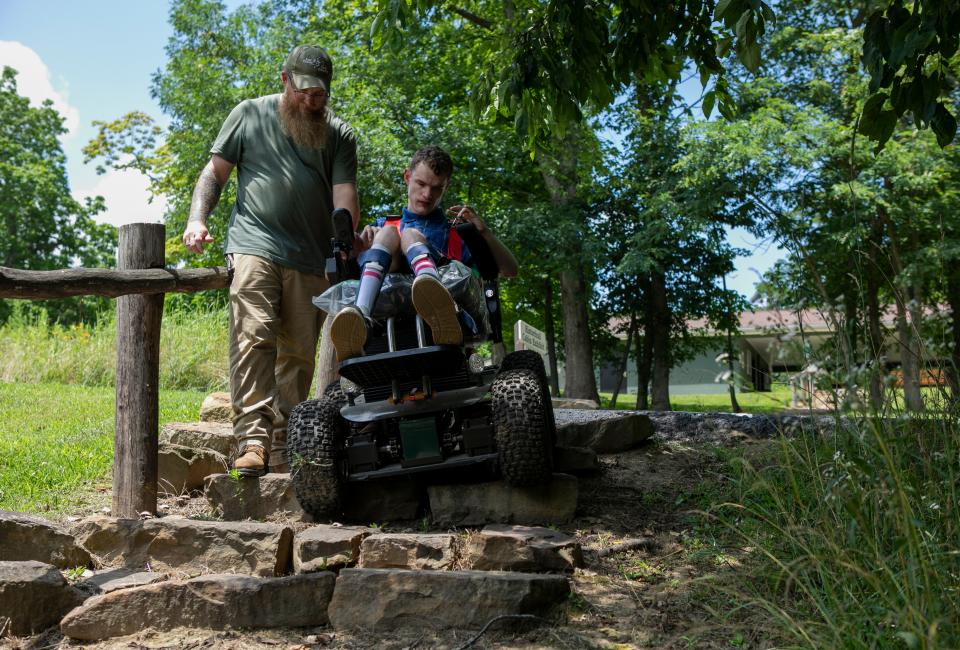 AJ Hawk, 21 of Chillicothe, uses an all terrain wheelchair to get down a set of stone stairs while his father Allen Hawk, Maintenance Supervisor for the Ross County Parks District, uses the steering mechanism to guide the wheelchair down the stairs while hiking on one of the trials at Buzzard's Roost Nature Reserve on July 21, 2023, in Chillicothe, Ohio. The wheelchair, which will soon be available for public use through the Ross County Parks District, gives people with disabilities like AJ, who has Cerebral Palsy, a chance to get out and enjoy the nature in Ross County.