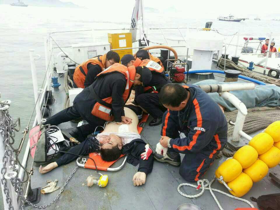 An injured passenger who was on a sinking ship, is rescued by South Korean maritime policemen, in the sea off Jindo