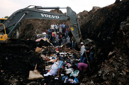 Rescue workers watch as excavators dig into a pile of garbage in search of missing people following a landslide when a mound of trash collapsed on an informal settlement at the Koshe garbage dump in Ethiopia's capital Addis Ababa, March 13, 2017. REUTERS/Tiksa Negeri