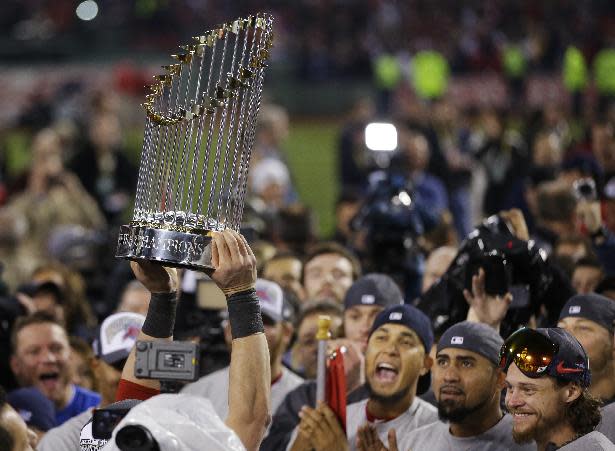 A player holds up the championship trophy after defeating the St. Louis Cardinals in Game 6 of baseball's World Series Wednesday, Oct. 30, 2013, in Boston. The Red Sox won 6-1 to win the series. (AP Photo/Matt Slocum)