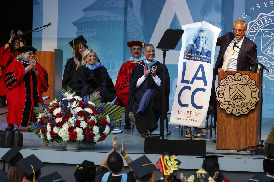 First lady Jill Biden, second from left, reacts as director of Los Angeles City College foundation Robert Schwartz, right, shows a poster of Biden at the Los Angeles City College commencement ceremony in Los Angeles, Tuesday, June 7, 2022. (AP Photo/Ringo H.W. Chiu)
