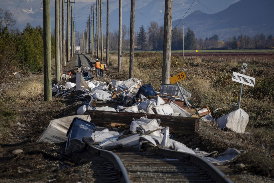 Southern Railway of British Columbia (SRY Rail Link) employees survey a section of rail lines that are washed out in numerous places and covered in debris after flood waters receded following heavy rains in Abbotsford, British Columbia, Friday, Nov. 19, 2021. (Darryl Dyck/The Canadian Press via AP)